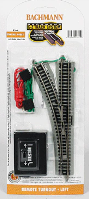 Bachmann Model Railroad 2-Track System with Remote Turnout Left, in its original blister card packaging. The set includes two curved track pieces with black rails and gray ties, a red and green wire with a black connector, and a black remote control.