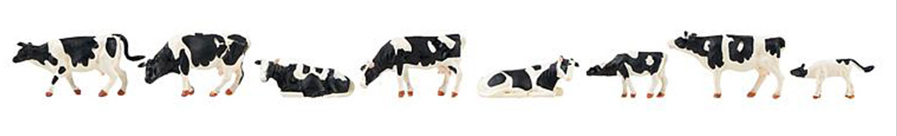A set of model figures depicting black and white cows, designed for use in model train sets.