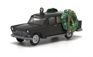 A black toy hearse with two green wreaths on the roof.