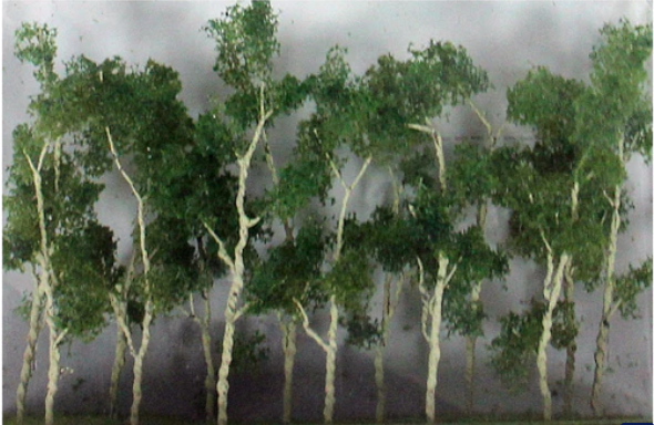 A group of three miniature model trees with green leaves, intended for use in model train setups.