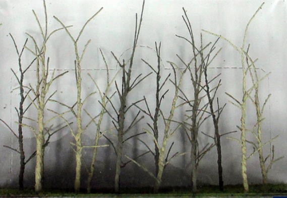 A set of model trees with a bare, wooden finish designed for use in a model train setup.