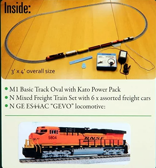 Kato N Scale Unitrack GE ES44AC GEVO Mixed Freight Train Set on a wooden surface, including a locomotive and assorted freight cars, a power pack, and track pieces.