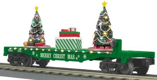 A green O-flat car with lighted Christmas trees on the sides, designed for a Christmas-themed train set.