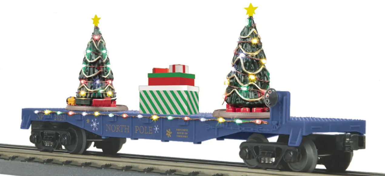 A blue toy train car with lighted Christmas trees on its side, designed to fit onto a track.
