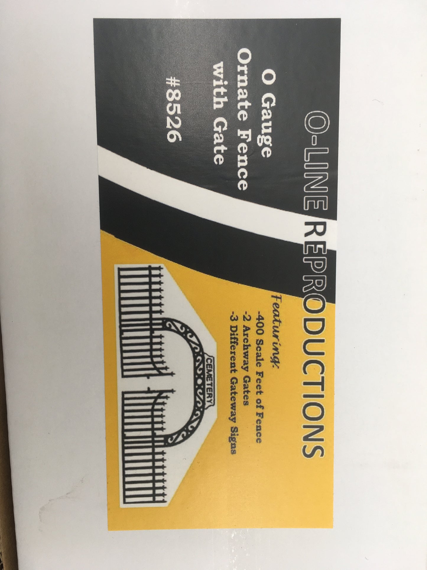 Packaging for O-Line Reproductions 8526 O Scale Ornate Fence with Gate, showing the product with a black and yellow design emphasizing the fence and gates.