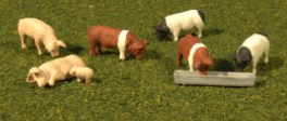 A set of toy pig figures for a model train set, in various sizes and colors, designed to complement the O SCALE system.