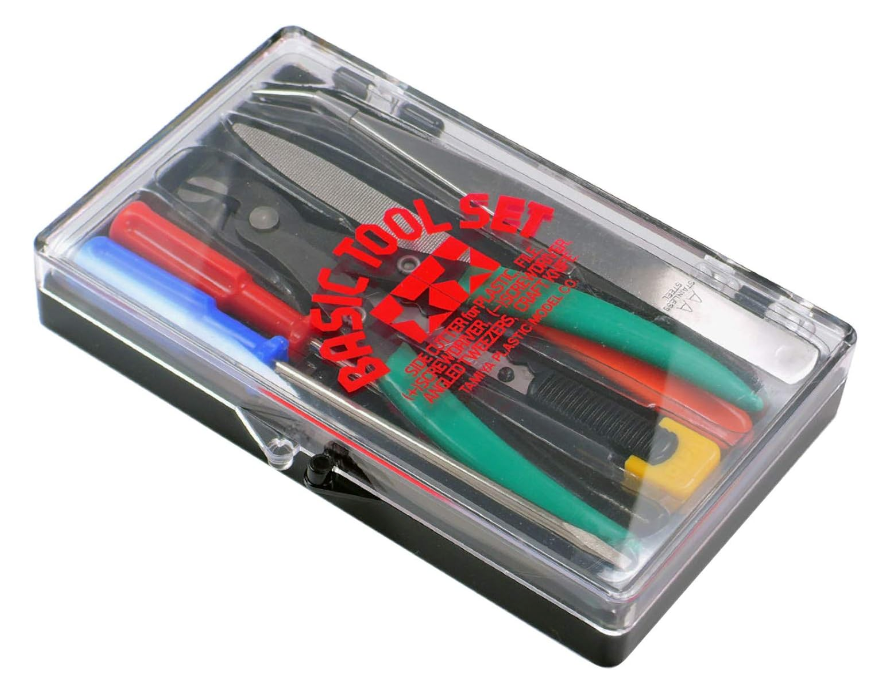 Tamiya Basic Tool Set in a plastic case, containing various tools such as scissors, tweezers, a craft knife, and a file, with a black base and clear cover.