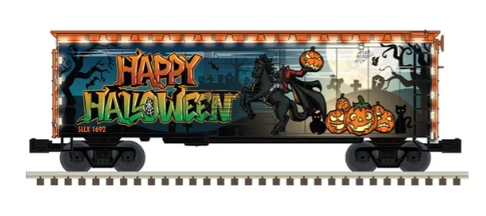A model train car with Halloween themed painting, including pumpkins and a witch on the side.