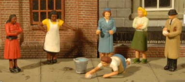 Three O scale sidewalk people figures in different poses, designed for use with model trains, depicted in a vintage style outdoor setting.
