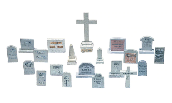 A collection of various tombstones and related scenic details designed for model train layouts, featuring different shapes and designs, including rectangular, square, and rounded tombstones, as well as obelisks, crosses, and spires.