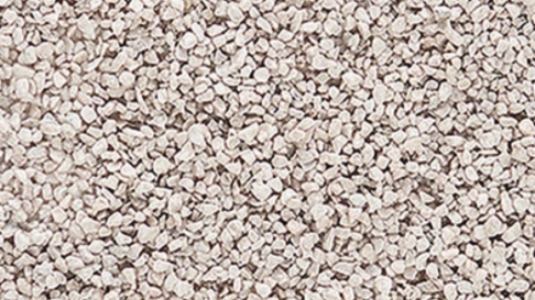 A close-up view of coarse white ballast for model train use, showing a textured surface.