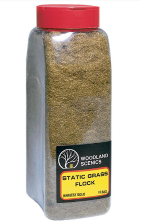 A bottleof Woodland Scenics Static Grass Flock in a Harvest Gold color, used for model train setups.