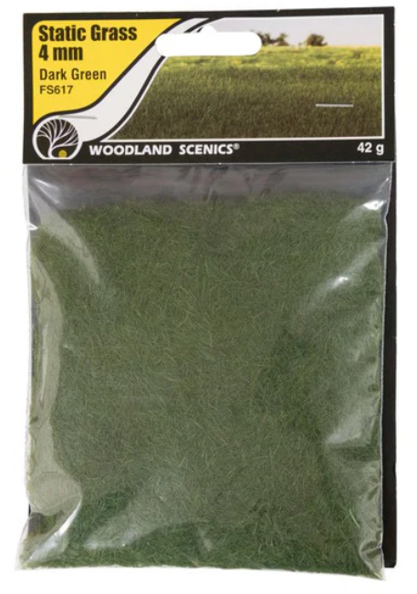 A package of Woodland Scenics FS617 Static Grass in dark green, weighing 4 grams, designed for use in model train setups.