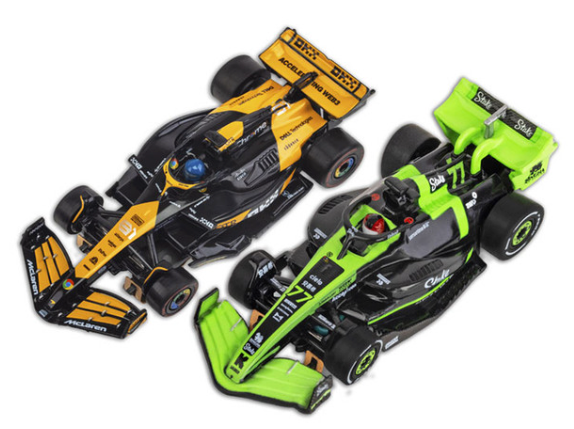 Two Formula 1 cars, one yellow and black, the other green and black, on a white background.