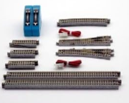 A set of miniature model train tracks and accessories, including several curved and straight rails, red ties, and a blue electrical switch component, arranged on a plain white background.