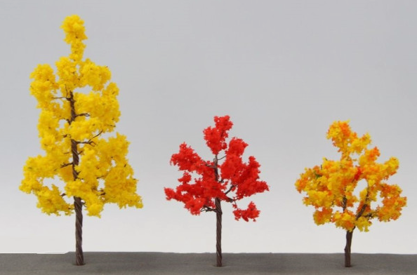 Three model trees with yellow, red, and orange foliage on a gray background