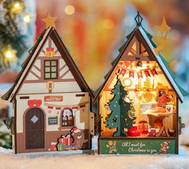 Two Christmas-themed wooden houses with lights and decorations on a blurred festive background.