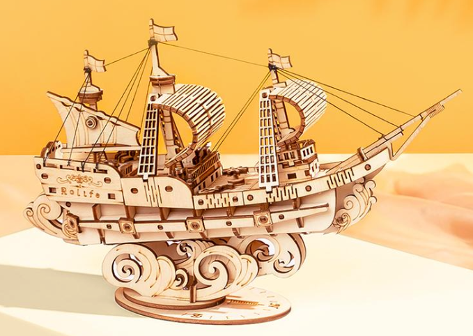 Wooden model ship on a white base with a yellow background