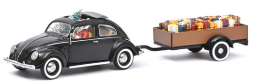 A diecast model of a black VW Beetle with a Christmas-themed trailer, displayed in an acrylic case.