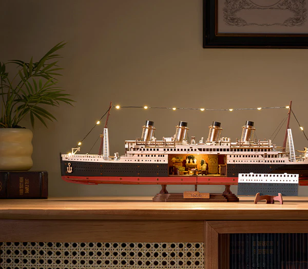 Model of the Titanic on a wooden table with decorative lights and a plant in the background.