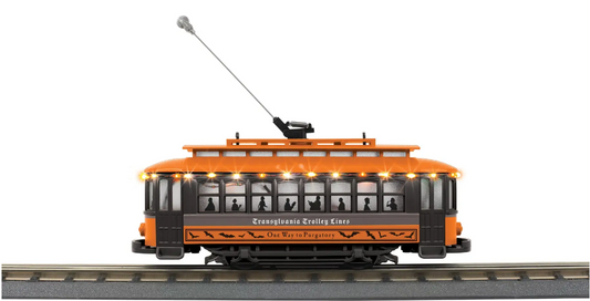 An orange and black toy trolley model train with a lighted interior and a long pole, set on tracks.