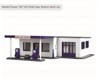 Model of a gas station with a white and purple facade, featuring pumps and a sign.