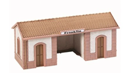 Model of a passenger wayside station with a red roof, white walls, and a brown platform.