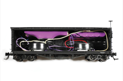 A digital sound decoder for model trains with various coloured wires coming out from it, predominantly in a black casing.