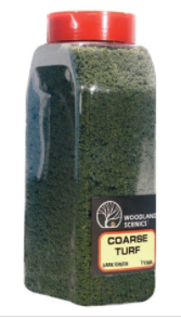 A plastic jar labeled 'Woodland Scenics Coarse Turf' with a red lid, filled with dark green model train accessory.