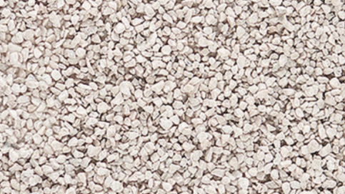 A close-up view of light gray coarse material, typically used as scenery ballast for model train setups.