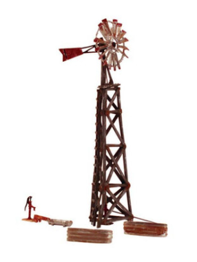 A model of an old windmill in N Scale, with a metal turbine, weathered wood tower, and accessories including two stock tanks, a hand pump, and a trough.