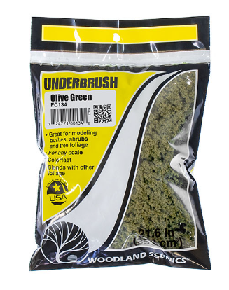 A bag of Woodland Scenics model train foliage in Olive Green color, intended for use with model trains and compatible with other foliage brands.