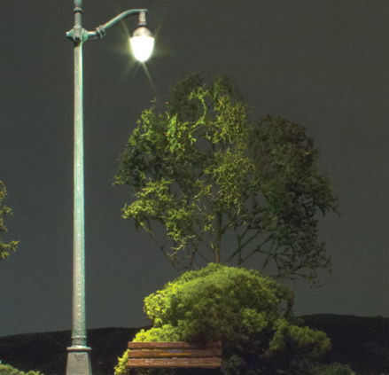 A model of an arched cast iron street light with a dark base and a light on top, set against a blurred background.
