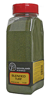 A container of Woodland Scenics model train scenery, green blend color, with a label showing the brand and product details.
